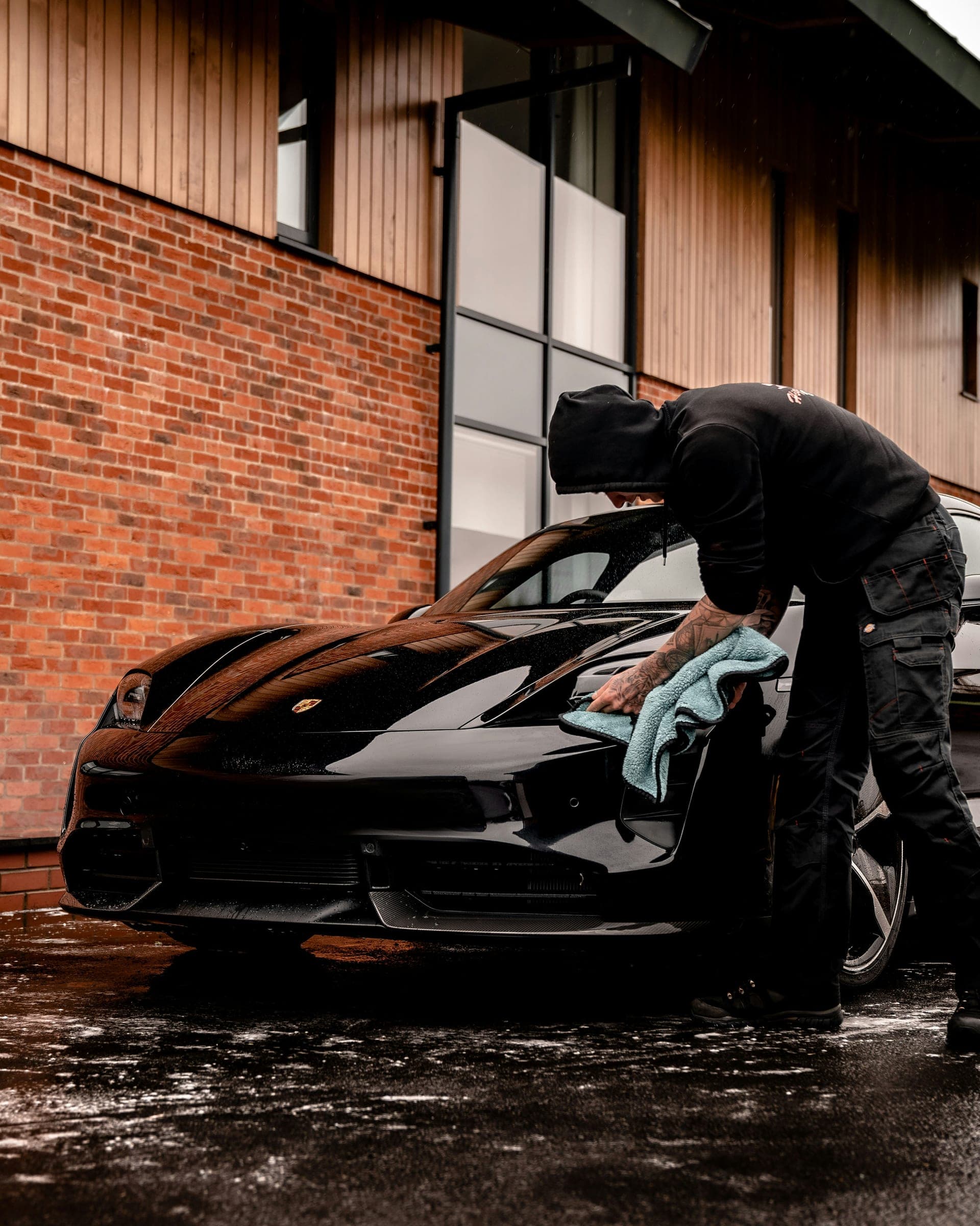 Detailer drying a black Porsche with a microfiber towel